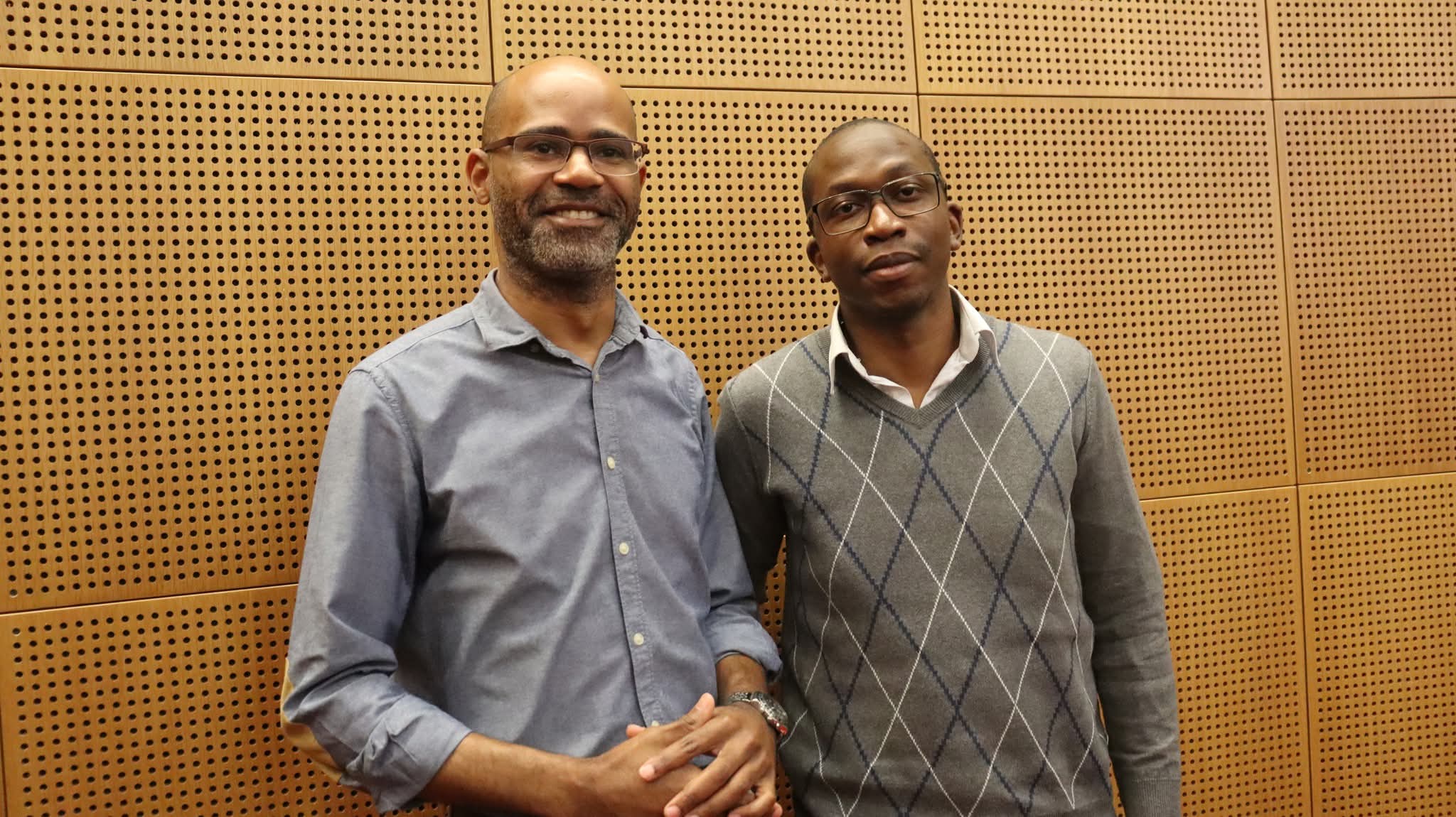 Dois homens em frente a painéis acústicos